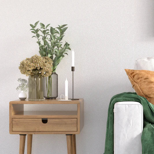 Wooden nightstand with decorative items next to a bed with pillows and blankets.